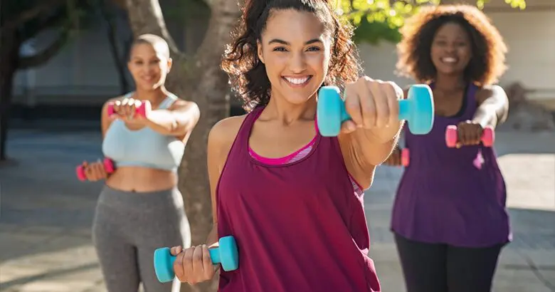 Three woman working out with light weights in the summer