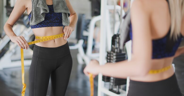 Woman measuring waist at gym